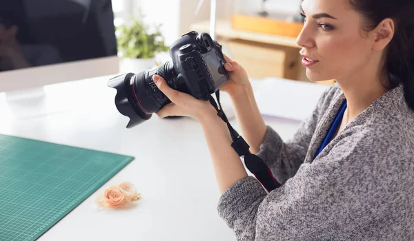 Jonge vrouw ontwerper staat in de buurt van de werkplek en fotograferen op digitale camera — Stockfoto