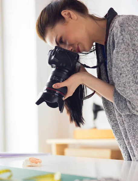 Jonge vrouw ontwerper staat in de buurt van de werkplek en fotograferen op digitale camera — Stockfoto