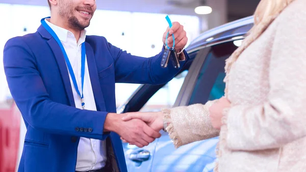 車の販売員は車の販売代理店で幸せな顧客に車を販売し、キーの上に手. — ストック写真