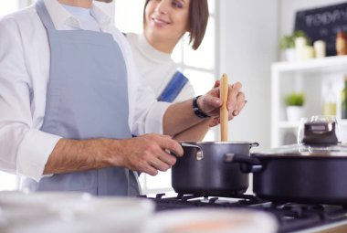 Evdeki mutfakta birlikte yemek pişiren çift.