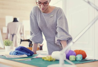 Güzel moda tasarımcısı stüdyoda duruyor.