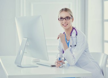 Hastanede masasında oturan genç bir kadın doktorun portresi.