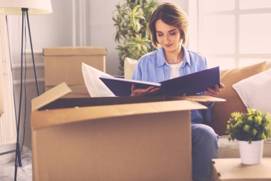 Genç bir kadın taşınıyor ve karton kutu paketliyor.