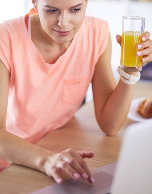 Mutfakta dizüstü bilgisayara benzeyen tariflerle gülümseyen genç bir kadın. Gıda blogcusu kavramı