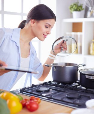 Mutfakta sobanın yanında duran genç bir kadın.