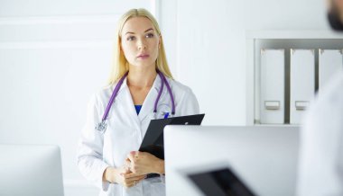 Kadın doktor hastanede dosyayla bekliyor.