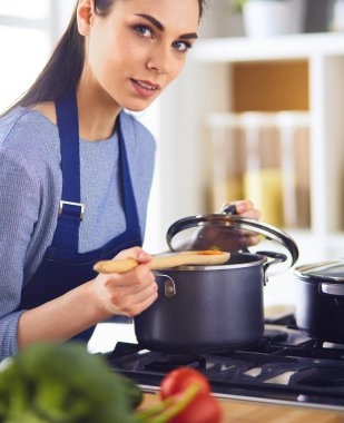 Mutfakta ahşap kaşıkla yemek pişiren kadın