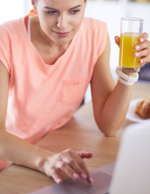 Mutfakta dizüstü bilgisayara benzeyen tariflerle gülümseyen genç bir kadın. Gıda blogcusu kavramı