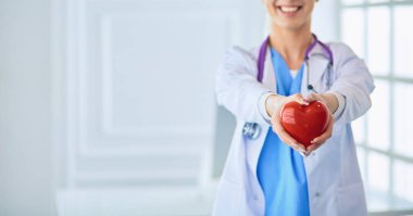 Stetoskoplu kadın doktor kollarında kalp tutuyor. Tıpta sağlık ve kardiyoloji kavramı