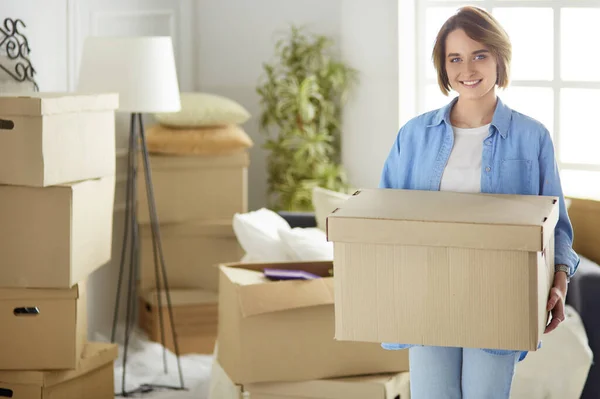 Portrait of pretty woman holding a box at new home — Stock Photo, Image