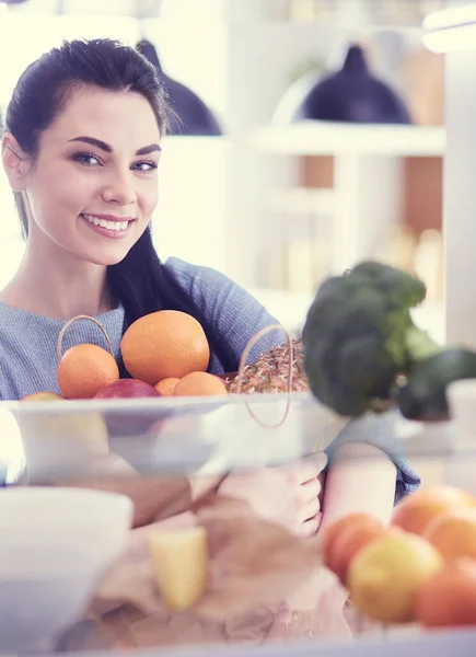 Lächelnde Frau holt frisches Obst aus dem Kühlschrank, gesundes Ernährungskonzept — Stockfoto