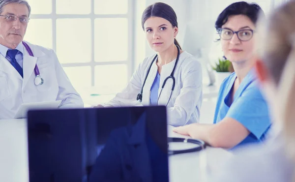 Equipo médico serio discutiendo casos de pacientes en un consultorio luminoso — Foto de Stock