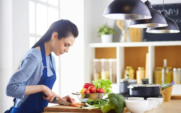 Молодая женщина режет овощи на кухне дома — стоковое фото