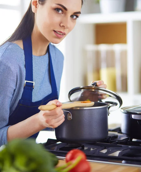 Cooking woman in kitchen with wooden spoon