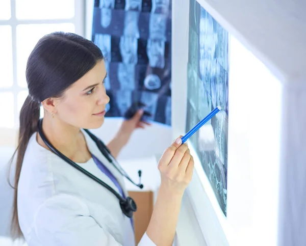 Jeune femme médecin souriante avec stéthoscope pointant vers la radiographie au cabinet des médecins — Photo