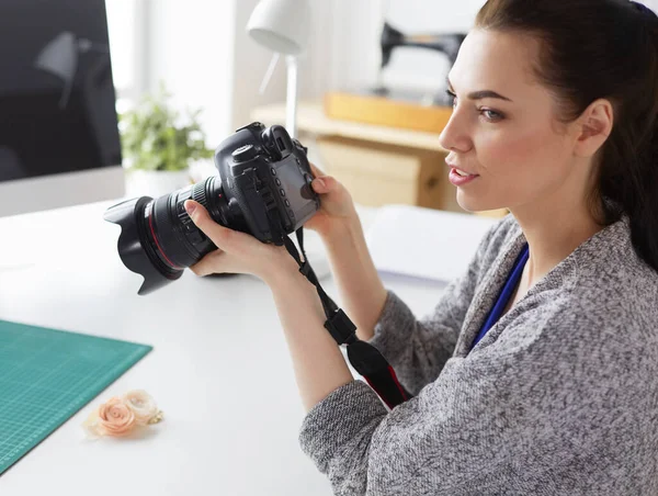 Jonge vrouw ontwerper staat in de buurt van de werkplek en fotograferen op digitale camera — Stockfoto