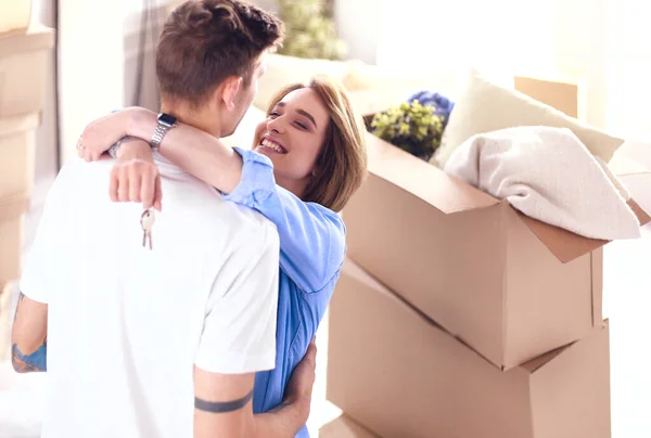 Jovem casal feliz abraçando, mostrando as chaves para a nova casa — Fotografia de Stock