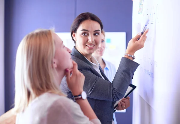 Business, formazione e concetto di ufficio - team di lavoro con flip board in ufficio discutendo di qualcosa. — Foto Stock