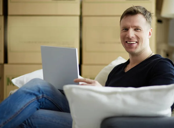 Retrato de un joven feliz mudándose a un nuevo hogar. Hombre sosteniendo tableta digital en sus brazos —  Fotos de Stock