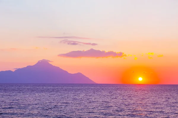 Silhouette of mount Athos at sunrise or sunset with light rays and sea panorama — Stock Photo, Image