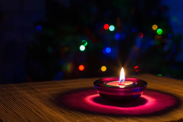 Natal fundo de férias com vela roxa e luzes coloridas — Fotografia de Stock