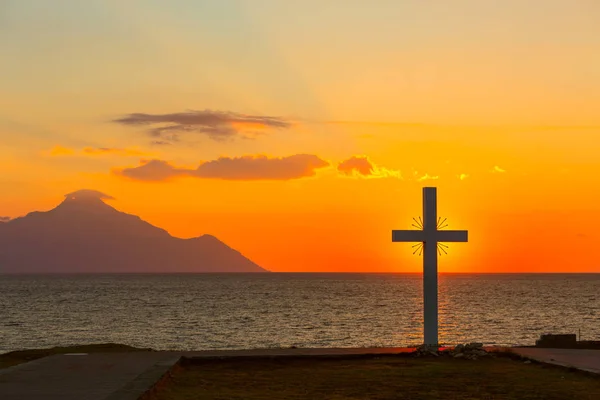 Silueta de cruz al amanecer o al atardecer con rayos de luz y vistas al mar — Foto de Stock