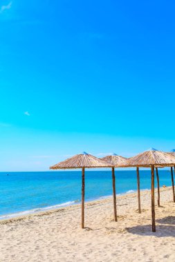Satır kumsal, deniz ve mavi gökyüzü ahşap şemsiye