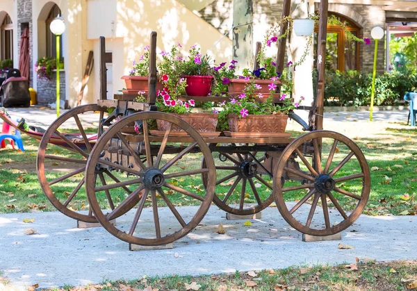 Carrinho de madeira velha com flores coloridas petúnias rosa — Fotografia de Stock