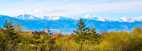 Spring landscape with wooden fence, trees, and snowy mountains — Stock Photo, Image