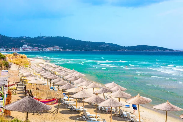 Strandhintergrund mit türkisfarbenen Meereswellen und Sonnenschirmen, Griechenland — Stockfoto