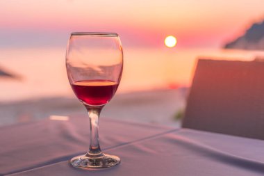 Gün batımında sahilde romantik bir kadeh şarap.