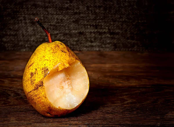 Een gebeten peer op een houten tafel — Stockfoto