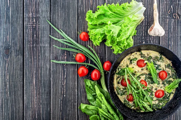 Fritatta ve malzemeler. Ahşap bir masada eski bir tava. Yukarıdan bak. Boş alan.