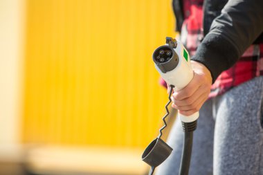 Mutlu kadın elektrikli araç şarj istasyonu üzerinde şarj