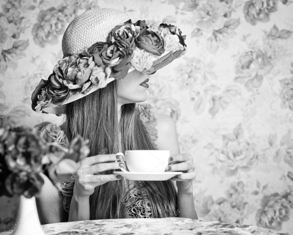 Black and white woman in a hat drinking tea