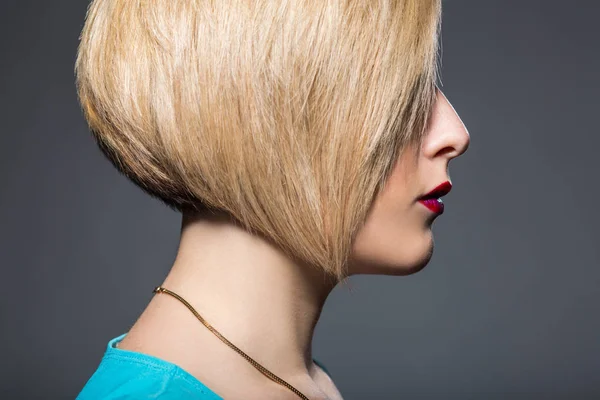 Mujer joven con corte de pelo corto de moda y maquillaje delineador brillante sobre fondo gris — Foto de Stock