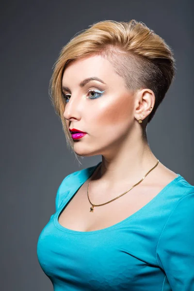 Ung kvinna med kort trendig frisyr och ljusa eyeliner smink över grå bakgrund — Stockfoto