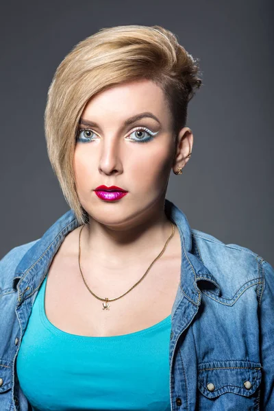 Ung kvinna med kort trendig frisyr och ljusa eyeliner smink över grå bakgrund — Stockfoto