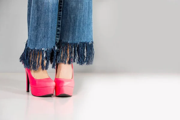 Female legs wearing high heels over grey background — Stock Photo, Image