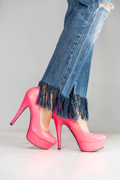 Female legs wearing high heels over grey background — Stock Photo, Image