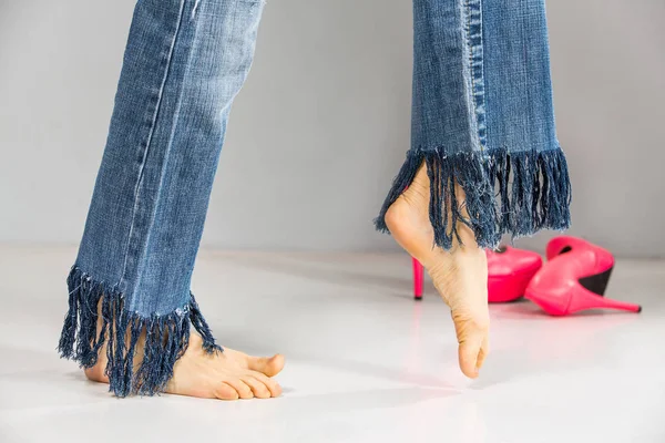 Bosý sexy nohy nosí džíny s třásněmi přes šedé pozadí — Stock fotografie
