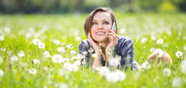 Jonge vrouw met behulp van mobiele telefoon in een weide voorjaar — Stockfoto