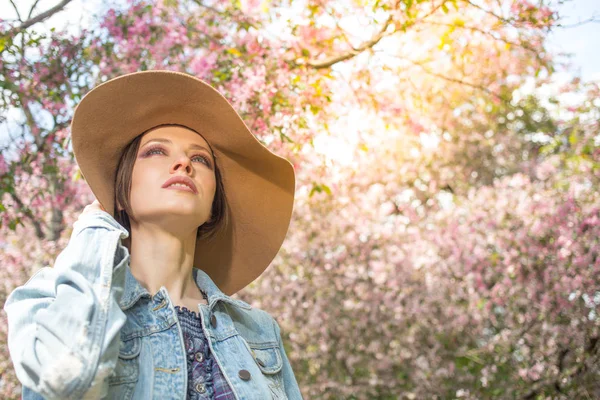 Pembe ağaçlar çiçek ve güneş ışığı ile bir parkta genç kadın — Stok fotoğraf