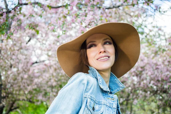 Pembe ağaçlar çiçek ile bir parkta genç kadın — Stok fotoğraf
