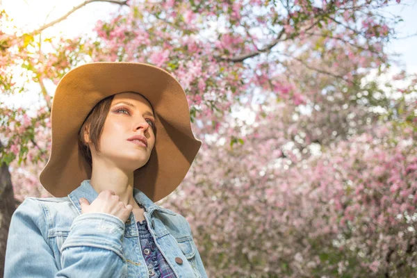 Pembe ağaçlar çiçek ile bir parkta genç kadın — Stok fotoğraf