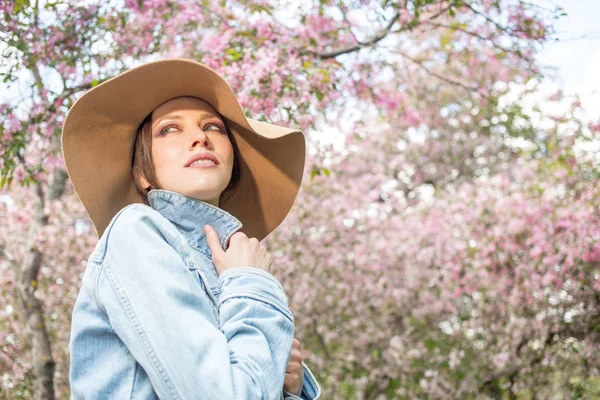 Ung kvinna i en park med rosa träd blomma — Stockfoto