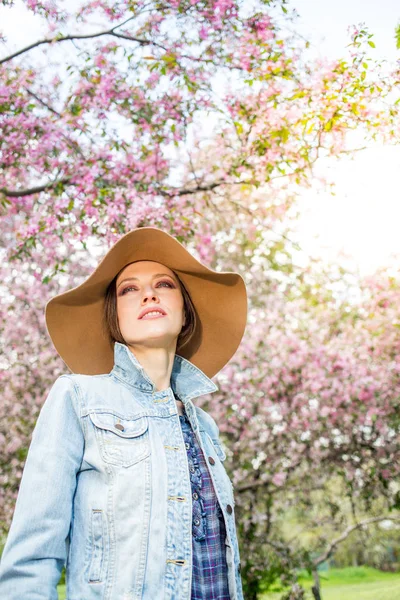 Молодая женщина в парке портрет в шляпе с пером — стоковое фото