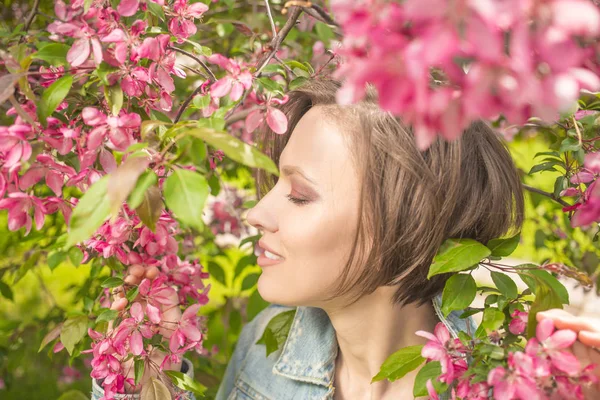 Jonge vrouw in een park met roze bomen bloem — Stockfoto
