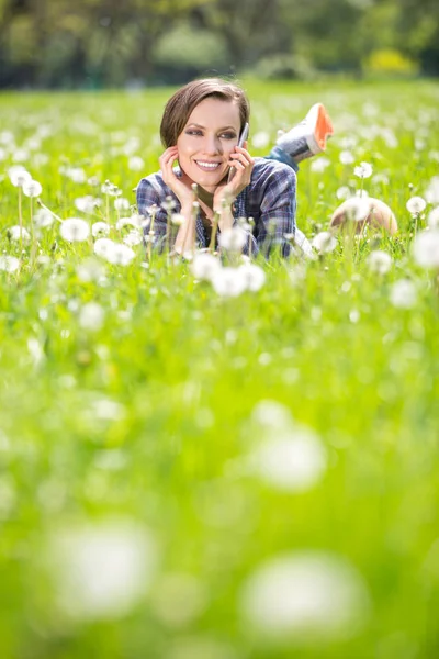 Jovem mulher usando telefone celular em um prado de primavera — Fotografia de Stock