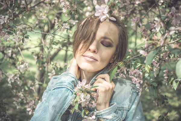 Mladá žena v parku se stromy růžový květ — Stock fotografie